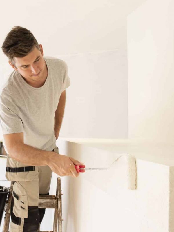 Shot of professional contractors standing on ladder and painting wall while refurbishing the apartment.