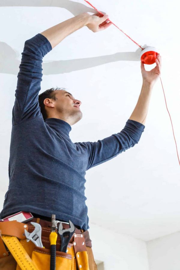 Electrician installing fire alarm system indoors